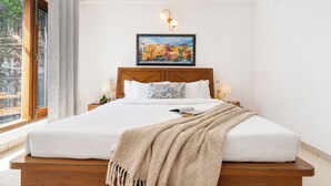 A neatly made bed with a headboard, a bedside lamp, and a framed painting above it. - Mist & Manor Petfriendly Apartments (Dilman)