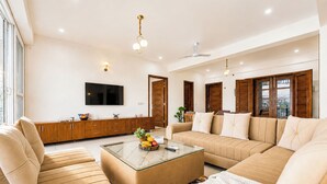 A modern living room with a sofa set, a coffee table, and a flat-screen TV mounted on the wall. - Mist & Manor Petfriendly Apartments (Dilman)