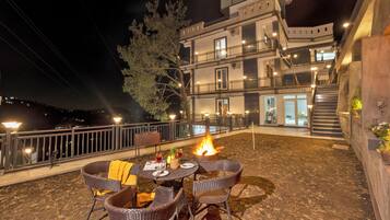 An outdoor patio with wicker chairs, a table, and a fire pit.