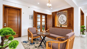 A room with a wooden door, a sofa, a small table, and a decorative wall piece. - Mist & Manor Petfriendly Apartments (Dilman)