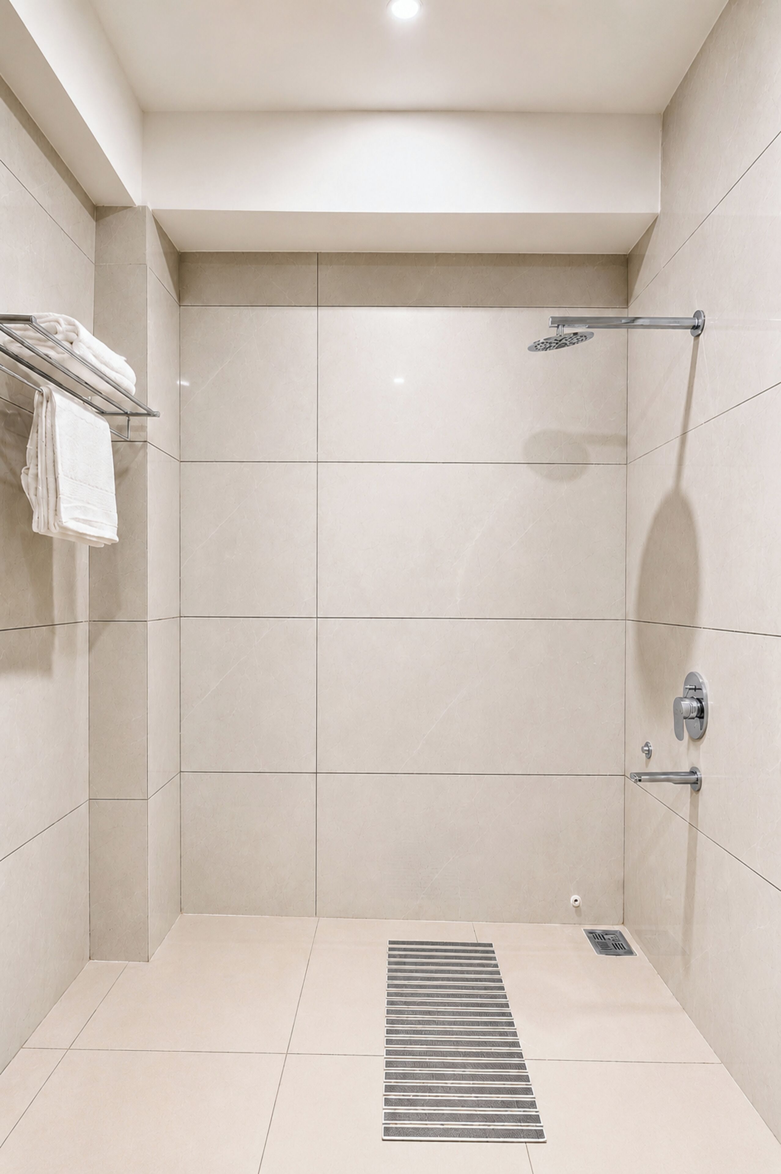 Una ducha moderna con puerta de vidrio, un perchero y un extractor.