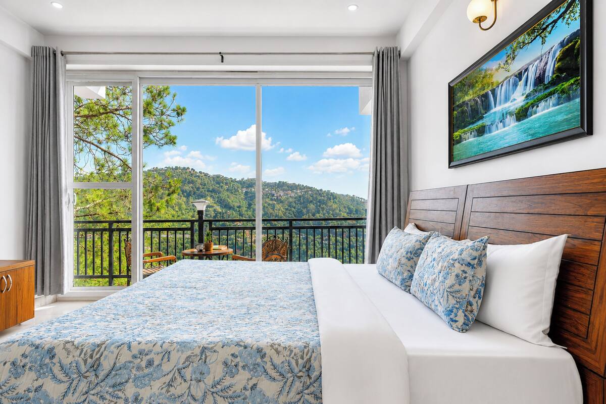 A bedroom with a large bed, a view of a balcony, and a painting of a waterfall.