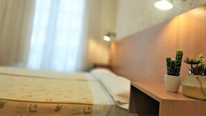 A hotel room with a bed, a bedside table with a cactus, and a wall-mounted light. - Roquefer Bilbao by gaiarooms (Bilbao)