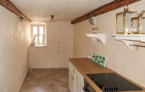 A kitchen with a wooden countertop, a stove, a window with a view, and a hanging light fixture. - 4 bedroom cozy home in Senj (Senj)