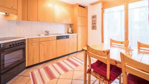 Una cucina moderna con mobili in legno, forno a incasso e zona pranzo con tavolo e sedie.