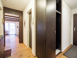Ein Flur mit Holzdielen, einer Tür mit Klingel und einem gerahmten Bild an der Wand.