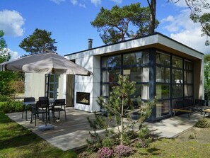 Ein modernes Haus mit Terrasse, Sitzgelegenheiten im Freien und einem Kamin.