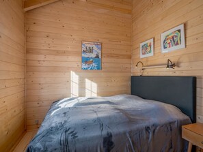 Een houten kamer met een bed, een poster aan de muur en twee ingelijste kunstwerken.