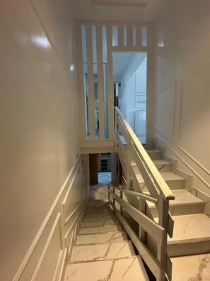 A staircase with marble steps and a wooden handrail, leading to an upper level. - 4bedroom Luxury Apartment (Lagos)