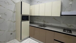 Ett modernt kök med väggar i marmor, en inbyggd mikrovågsugn, en diskho och en gasspis.