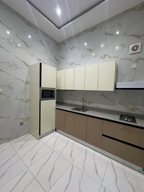 A modern kitchen with marble walls, a built-in microwave, a sink, and a gas stove. - 4bedroom Luxury Apartment (Lagos)