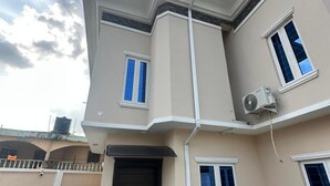 Un bâtiment à deux étages avec une porte marron foncé, des fenêtres à cadre blanc et une façade beige.