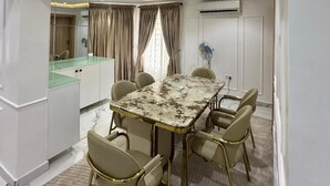 Un espace repas moderne avec une table en marbre, des chaises de couleur beige et une cloison en verre.