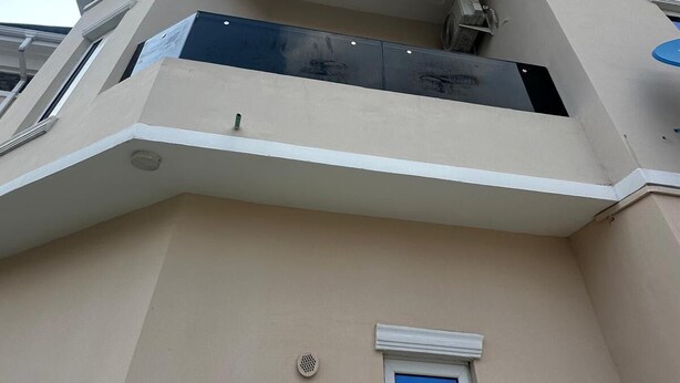 Un immeuble doté d’un balcon, d’une petite fenêtre et d’un appareil de climatisation visible.