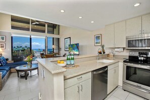 A modern kitchen with a central island, stainless steel appliances, and a view of the ocean. - Napili Point 2 Oceanfront Villas, Sleeps 8 | Car Incl. w/ 6 nights | ML-4106 by KBM (Lahaina)