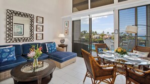 A modern living room with a sofa, dining table, and chairs, large windows with a view, and decorative wall art. - Napili Point 2 Oceanfront Villas, Sleeps 8 | Car Incl. w/ 6 nights | ML-4106 by KBM (Lahaina)