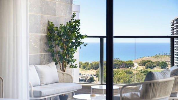Un balcón con vistas al mar, un sofá, una silla y una pequeña mesa.