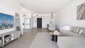 Una sala de estar moderna con una televisión de pantalla plana, un sofá, una mesa de centro y un comedor con sillas.