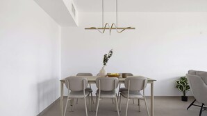 Un comedor moderno con una mesa rectangular, seis sillas, un florero con planta y una lámpara colgante.