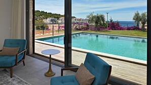 Una habitación con un ventanal grande, una piscina y dos sillas azules.