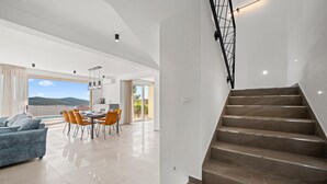 Ein modernes Interieur mit Treppe, Essbereich und Blick ins Freie.