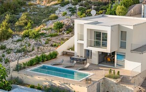 A modern two-story house with a pool, outdoor seating, and a view of a rocky hillside. - Awesome home in Zaboric (Zaboric)
