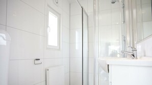 Une salle de bain comprenant des toilettes, une douche avec des portes en verre et un lavabo avec un miroir.