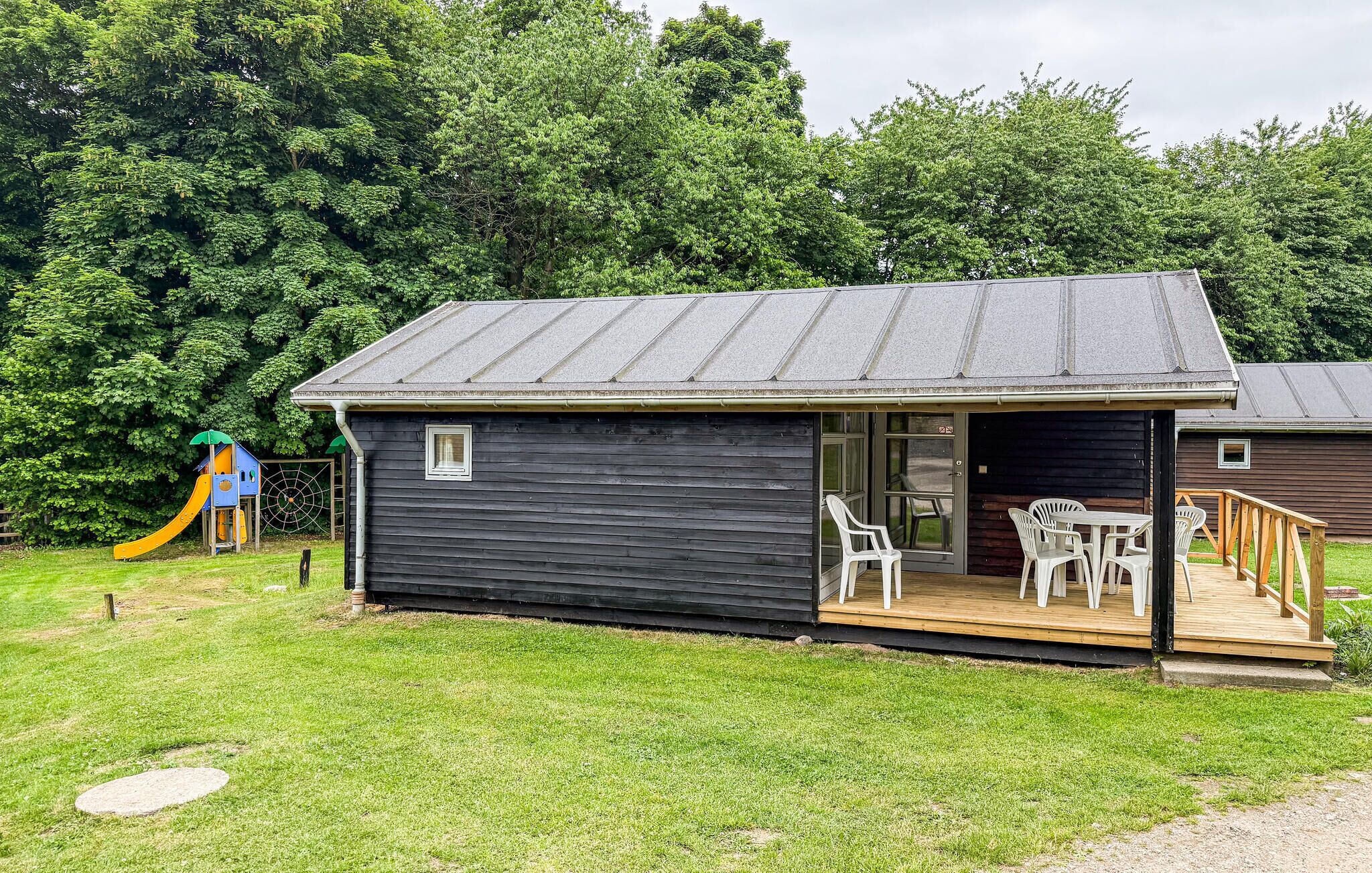 A small cabin with a deck, a slide, and a door leading to an outdoor area.