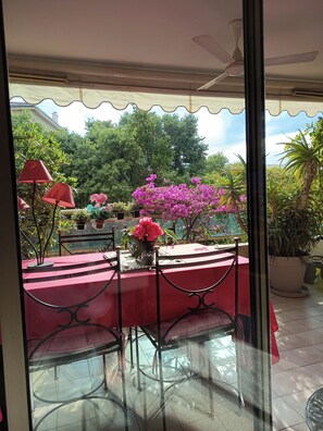 Ein verglaster Patio mit einem roten Tisch, Stühlen und Topfpflanzen.