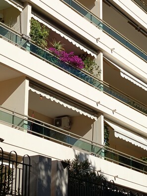 Ein mehrstöckiges Gebäude mit Balkonen, von denen einige mit Pflanzen und Blumen bepflanzt sind.