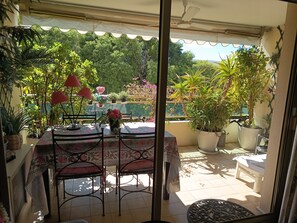 Eine Terrasse mit Tisch und Stühlen, umgeben von Blumentöpfen und Blick ins Grüne.