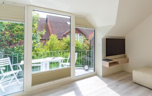Un apartamento moderno con balcón, televisor y sofá.