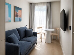 Ein modernes Wohnzimmer mit einer Couch, zwei Sessel, einem kleinen Tisch und einem flachbildschirmfernseher an der Wand.