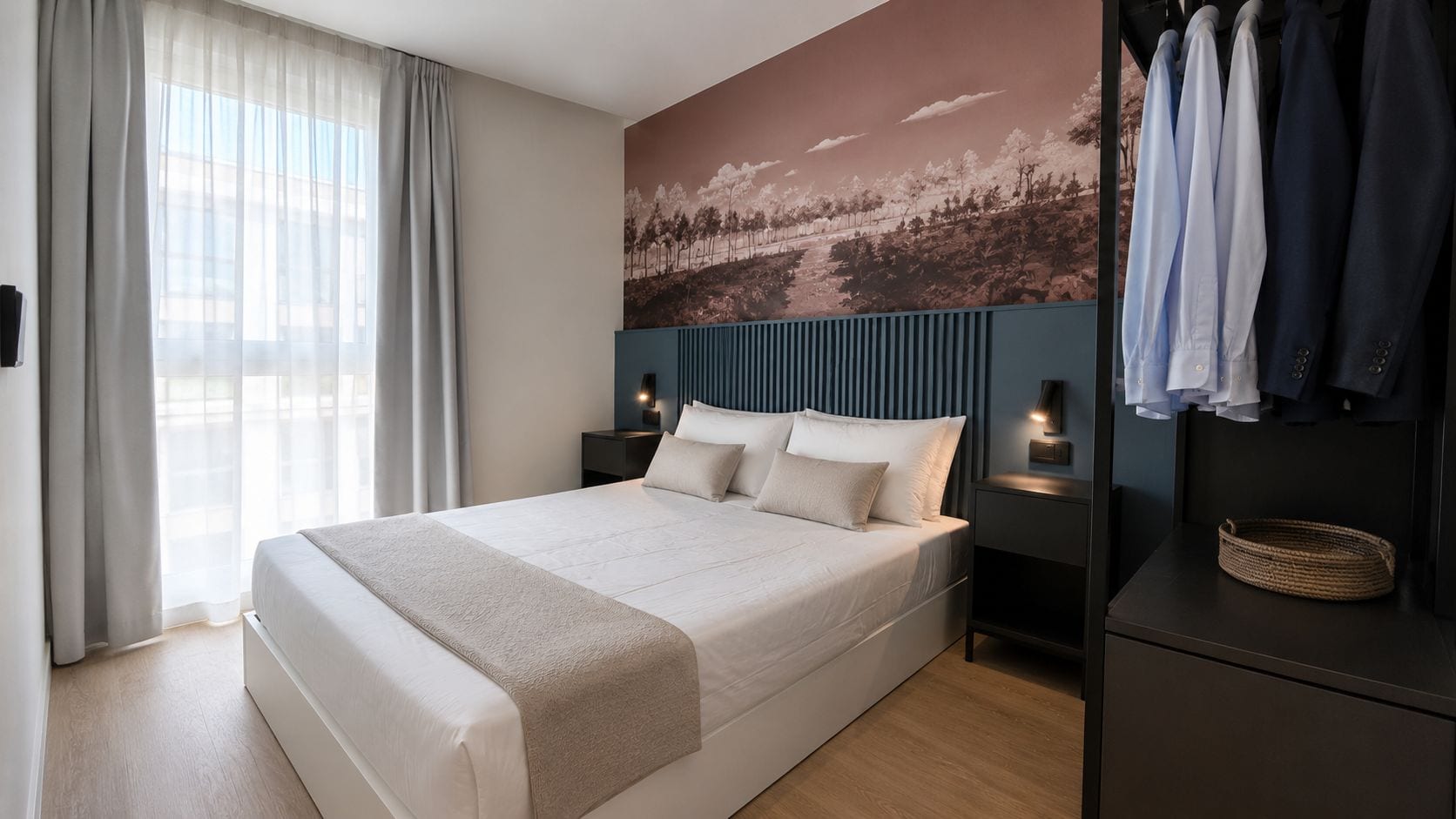 Una camera d'hotel moderna con un letto grande, un armadio, un comodino con lampada e un'opera d'arte appesa al muro.