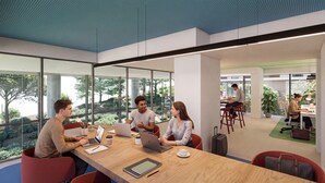 Un ufficio moderno con ampie finestre, un tavolo in legno e persone al lavoro alle scrivanie.