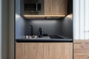 A modern kitchen with a built-in microwave, a coffee maker, and a sink.