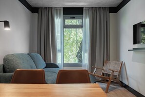 A modern room with a sofa, a dining table, and a television.