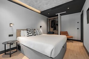 A modern bedroom with a large bed, bedside table, and a chair.