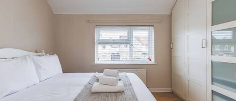A bedroom with a large bed, a window, and a wardrobe.