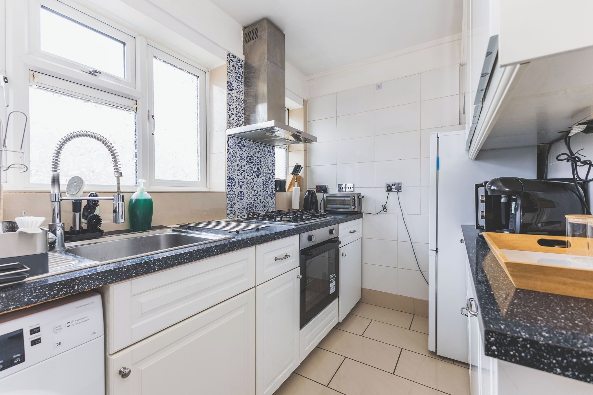 A modern kitchen with a stainless steel sink, a built-in oven, and a range hood.