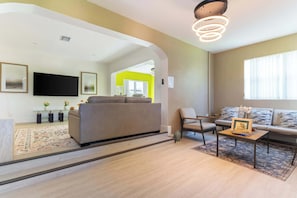 A modern living room with a sofa, a coffee table, and a TV. - Hollywood 3BR - Private Pool & Fire Pit (Hollywood)