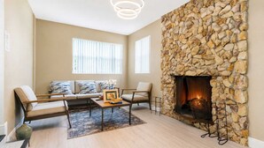 Ein Wohnzimmer mit Kamin aus Stein, einer Sofagarnitur und einem Couchtisch.