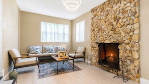 A living room with a stone fireplace, a sofa set, and a coffee table. - Hollywood 3BR - Private Pool & Fire Pit (Hollywood)