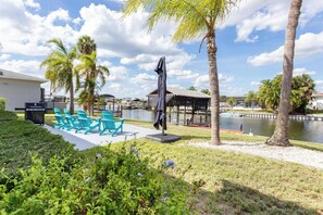 A poolside area with chairs, a grill, and a covered seating area. - ‼️Apollo Beach Waterfront - Boat Slip & Patio (Apollo Beach)