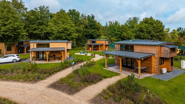 A row of modern cabins with a gravel path leading to them, surrounded by lush greenery. - Holiday Home in Kaatsheuvel With Terrace (Kaatsheuvel)