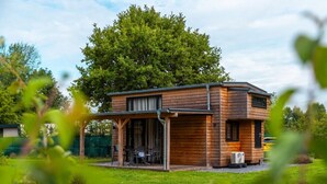 A two-story wooden house with a covered patio and a carport. - Holiday Home in Kaatsheuvel With Terrace (Kaatsheuvel)