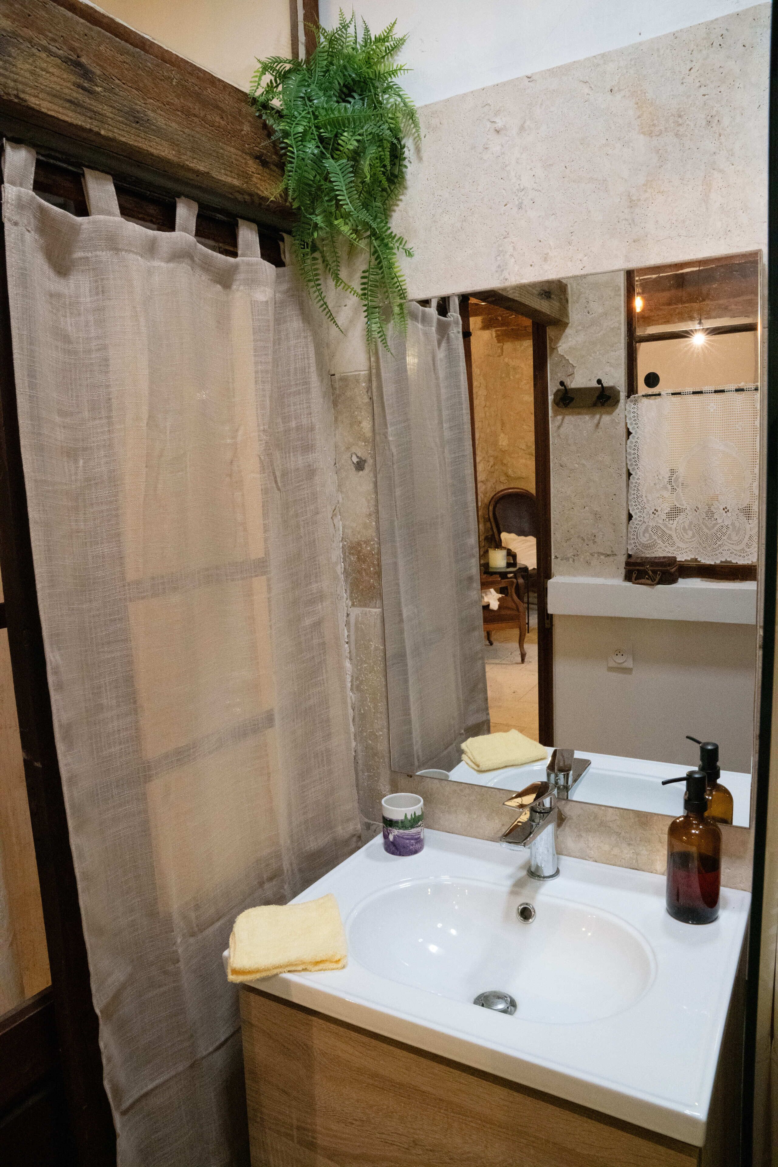 A bathroom with a wooden vanity, a sink, a mirror, a towel, and a plant.