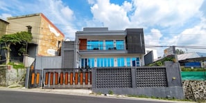 A modern two-story house with a gated entrance, a balcony, and a large window.