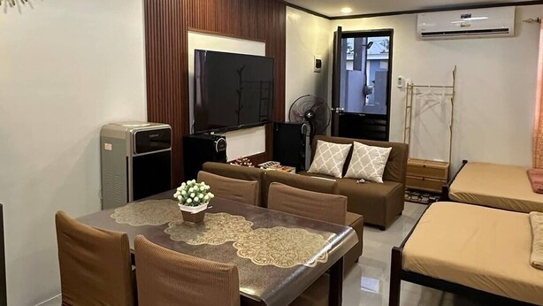 A modern living room with a dining area, a sofa set, a TV, and an air conditioning unit.
