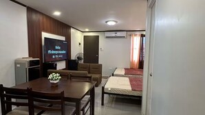 A modern living room with a dining area, a TV, and a bed.